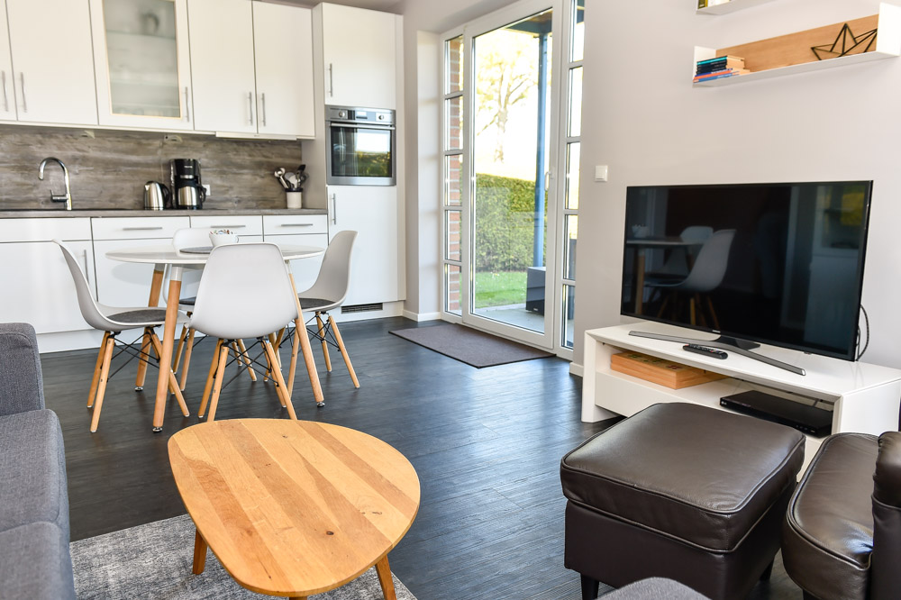 Blick vom Wohnbereich mit Fernseher und Sofa in Richtung Küche